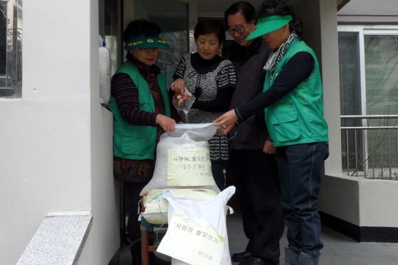 ▲이매2동 주민들이 아파트 출입구에 마련된 수미통에 쌀을 모으고 있다.